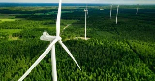 Aerial view of windmills in green summer forest in Finland. Wind turbines for electric power with clean and Renewable Energy