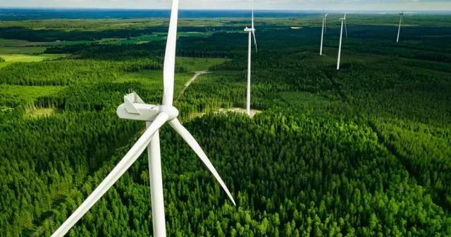 Aerial view of windmills in green summer forest in Finland. Wind turbines for electric power with clean and Renewable Energy