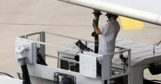 Airport worker refueling an airplane before take off.