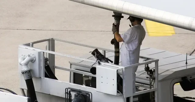 Airport worker refueling an airplane before take off.