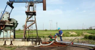 Worker with wrench on oil field