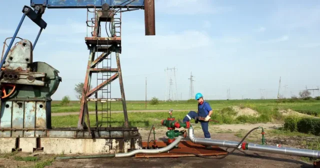 Worker with wrench on oil field