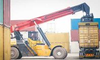 Forklift putting shipping container on cargo rail